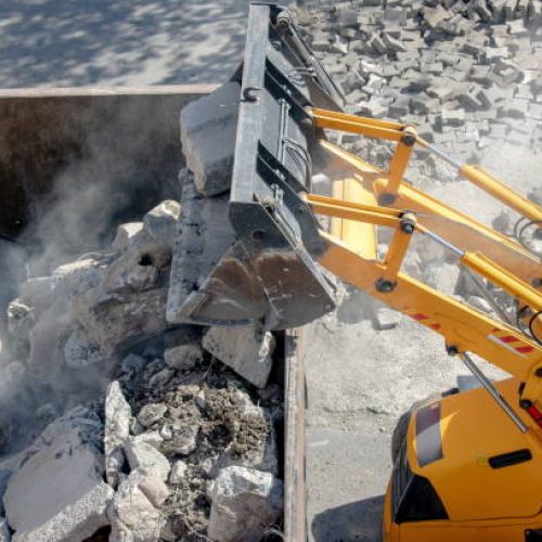 Bulldozer loader uploading concrete debris into dump truck at construction site Concrete demolition with a bulldozer in East Valley, AZ