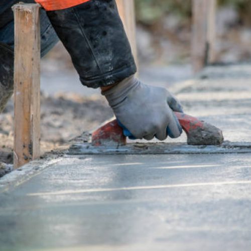 A construction worker is Smoothing wet cement Worker smoothing a concrete foundation in East Valley, AZ